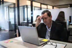 Worried mature businessman working using a laptop at office